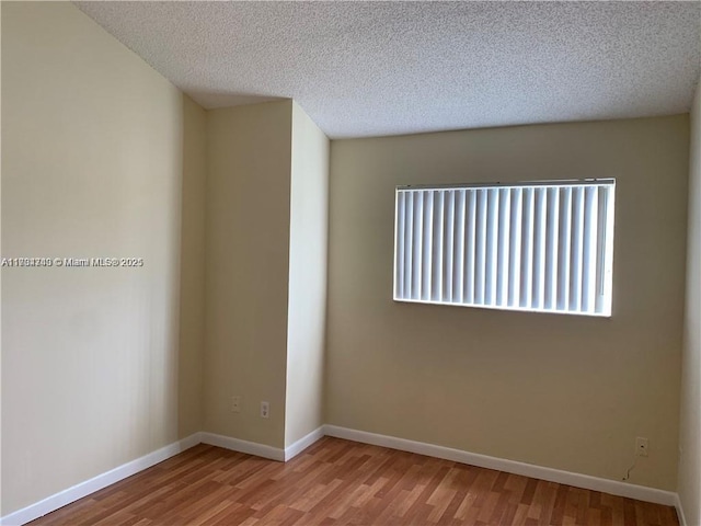 spare room with wood-type flooring and a textured ceiling