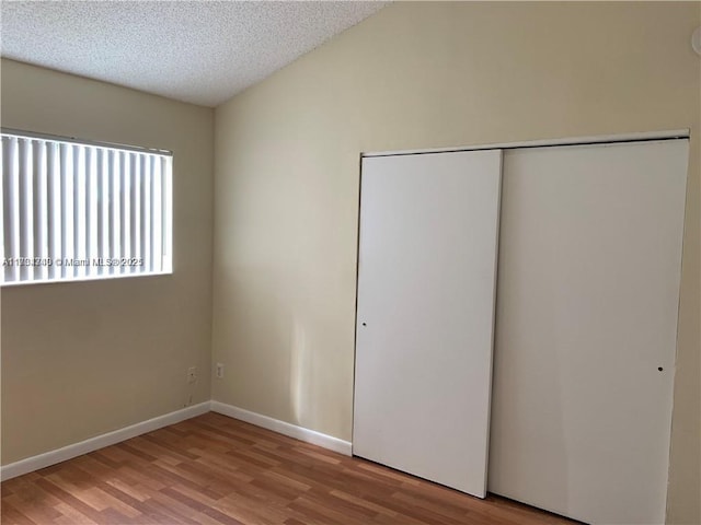 unfurnished bedroom with a closet, a textured ceiling, and light hardwood / wood-style flooring