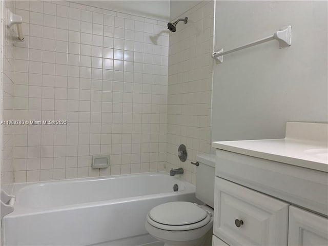 full bathroom featuring tiled shower / bath, vanity, and toilet