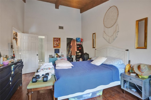 bedroom with beam ceiling, dark wood-type flooring, wooden ceiling, and a high ceiling