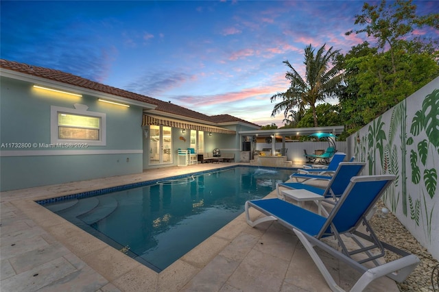 pool at dusk featuring a patio area