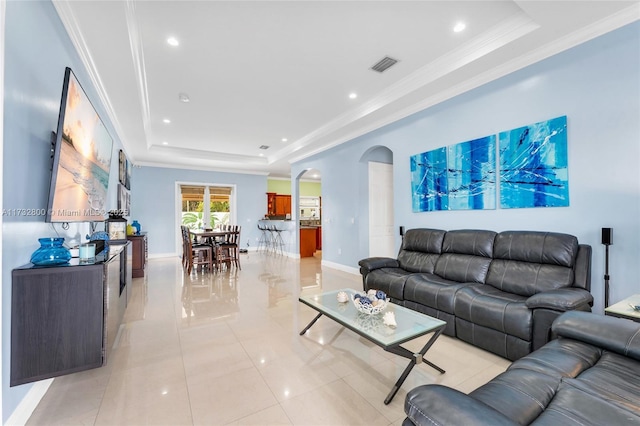 living room with light tile patterned flooring, crown molding, and a tray ceiling