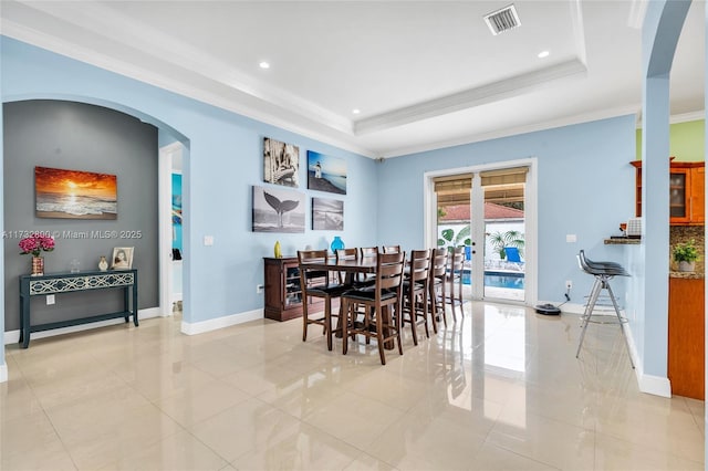 tiled dining room with ornamental molding, a raised ceiling, and french doors