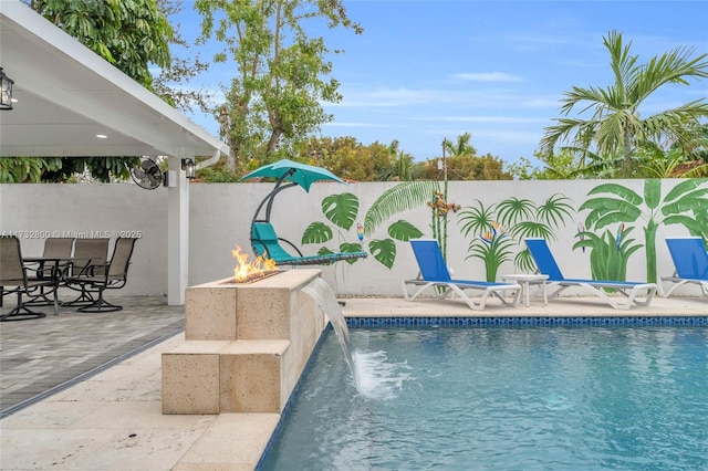 view of swimming pool featuring pool water feature, a fire pit, and a patio