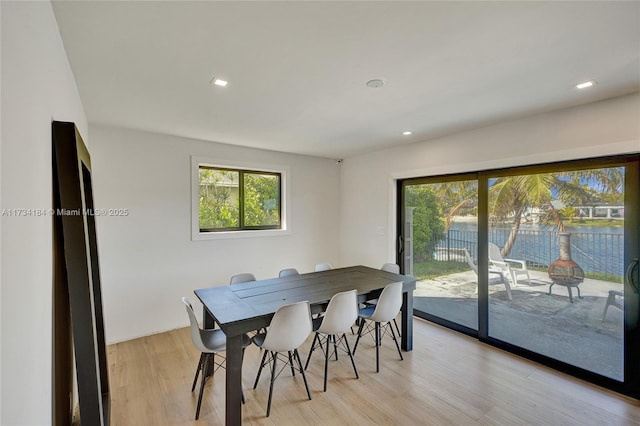 dining space with a water view and light hardwood / wood-style flooring