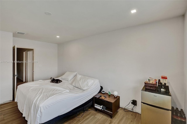 bedroom featuring stainless steel fridge and light wood-type flooring