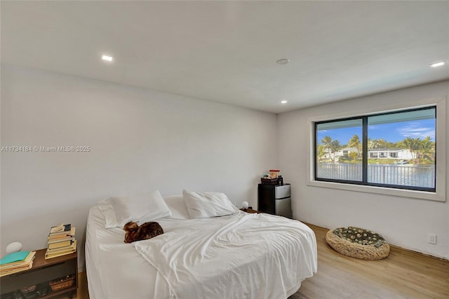 bedroom featuring hardwood / wood-style flooring and a water view