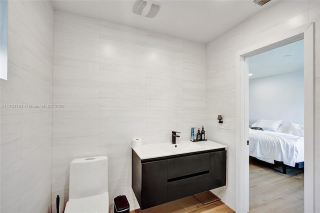 bathroom with vanity, hardwood / wood-style flooring, toilet, and tile walls