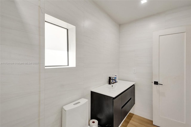 bathroom with hardwood / wood-style floors, sink, tile walls, and toilet