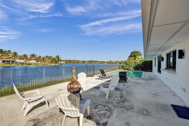 view of patio featuring a fenced in pool, a water view, and an outdoor fire pit