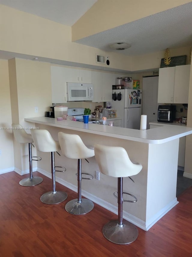 kitchen with white appliances, kitchen peninsula, and a kitchen bar