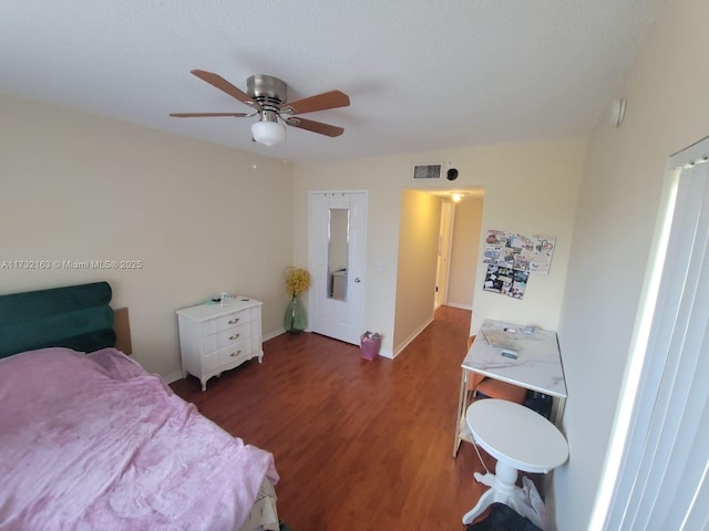 bedroom featuring dark wood-type flooring, ceiling fan, and a textured ceiling