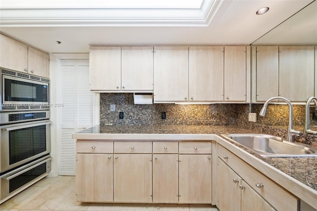 kitchen with stainless steel appliances, light brown cabinetry, sink, and backsplash