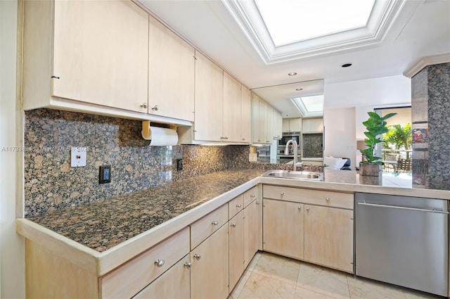 kitchen with light brown cabinetry, sink, a skylight, stainless steel dishwasher, and kitchen peninsula