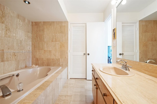 bathroom featuring vanity, a relaxing tiled tub, and tile patterned floors