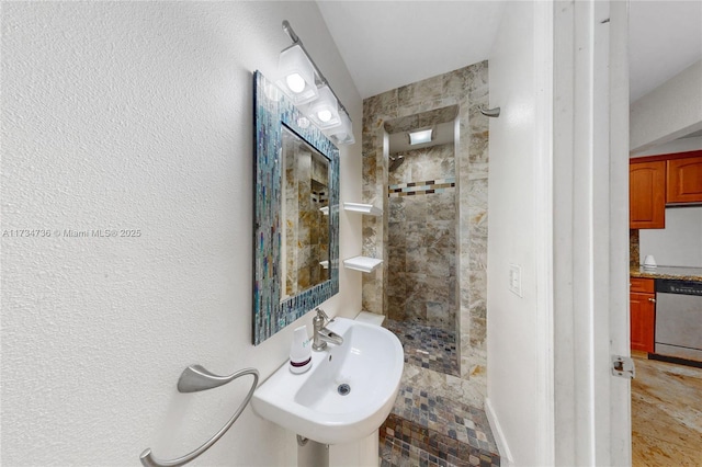 bathroom with a tile shower and sink