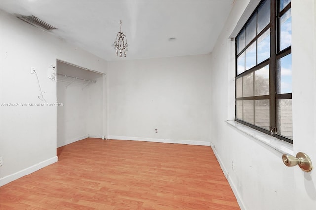 unfurnished room with an inviting chandelier and hardwood / wood-style floors