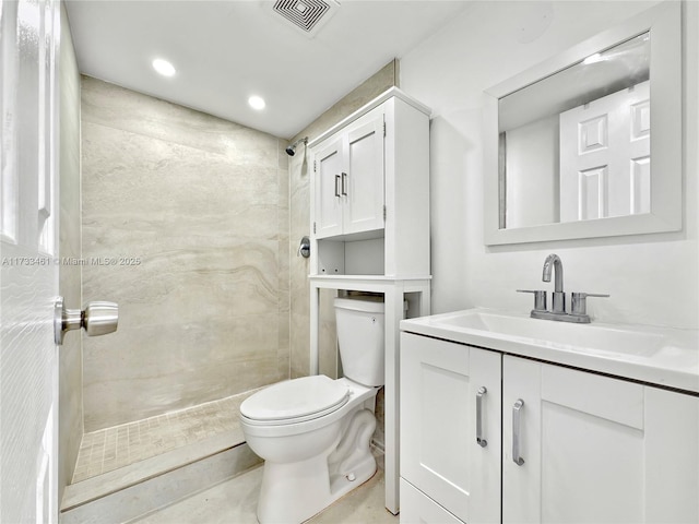 bathroom featuring vanity, tiled shower, and toilet