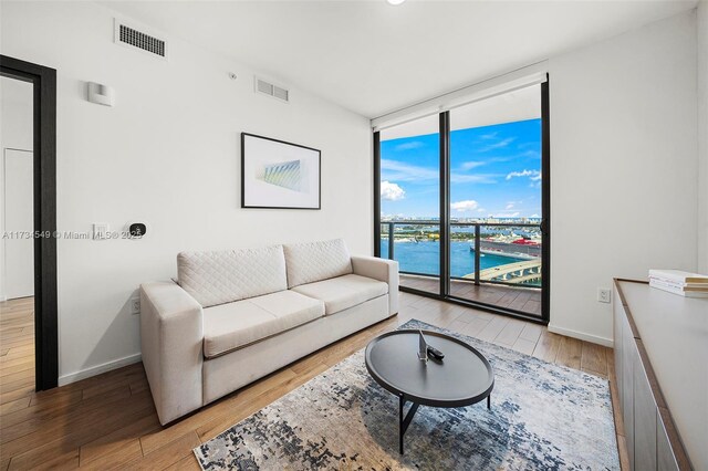 living room with a water view, expansive windows, and light wood-type flooring