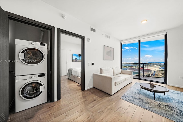 laundry room featuring stacked washing maching and dryer, visible vents, laundry area, and light wood-style floors