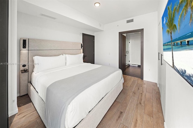 bedroom featuring wood finished floors, visible vents, and baseboards