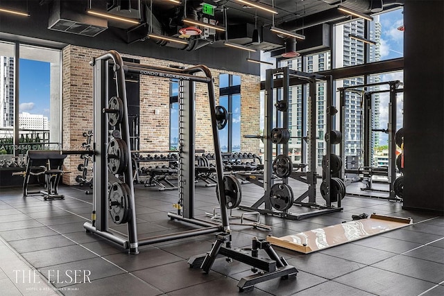 gym with a view of city, expansive windows, and brick wall