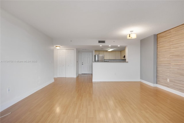 unfurnished living room featuring baseboards, light wood-style floors, and visible vents