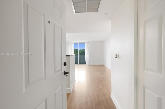 hall with visible vents, light wood finished floors, and baseboards