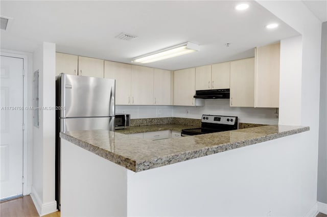 kitchen with cream cabinetry, stainless steel appliances, kitchen peninsula, and stone counters