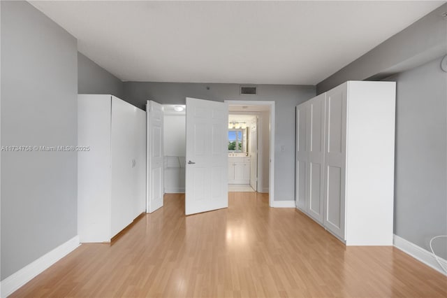 interior space with light wood finished floors, baseboards, and visible vents