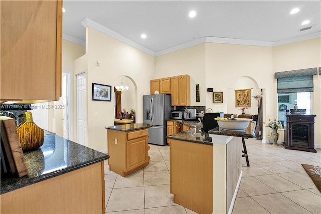 kitchen featuring a center island, light tile patterned floors, stainless steel fridge, and dark stone counters