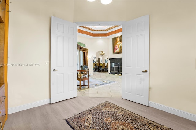 corridor featuring hardwood / wood-style flooring, ornamental molding, and a tray ceiling