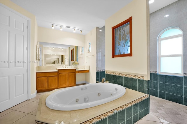 bathroom with vanity, tiled tub, tile patterned floors, and tile walls