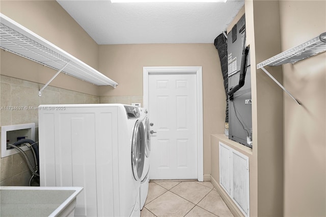 clothes washing area featuring light tile patterned floors, a textured ceiling, and washer and clothes dryer