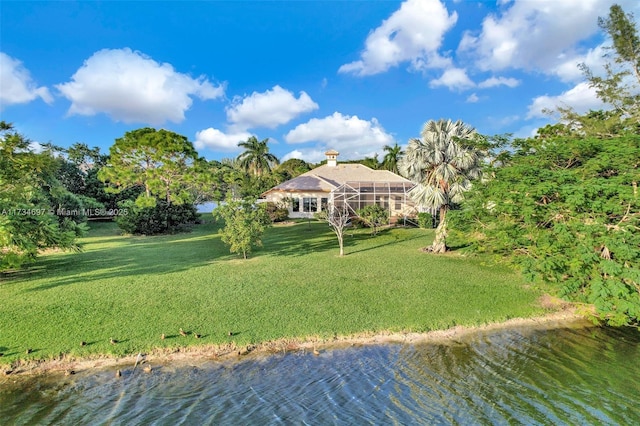 rear view of property featuring a lanai, a water view, and a lawn