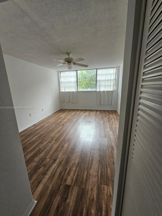 empty room with dark wood-type flooring, ceiling fan, and a textured ceiling