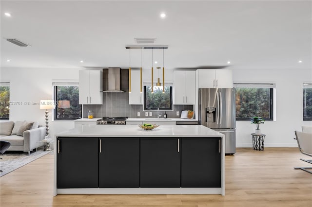 kitchen with a large island, decorative light fixtures, wall chimney exhaust hood, and stainless steel refrigerator with ice dispenser