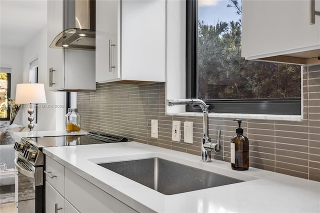 kitchen with white cabinets, stainless steel electric range oven, sink, and wall chimney range hood