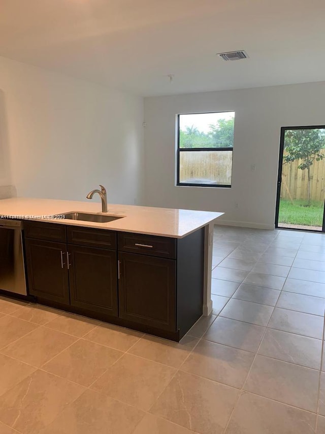 kitchen featuring light tile patterned flooring, stainless steel dishwasher, sink, and dark brown cabinets