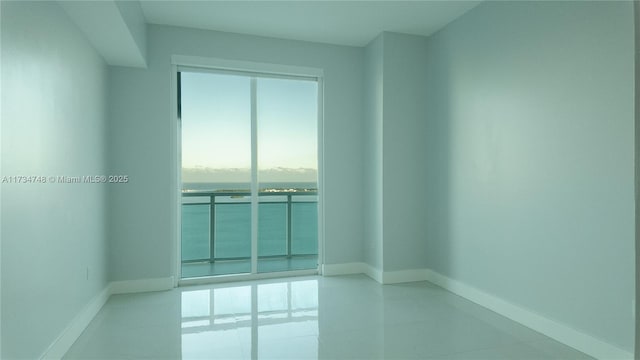 spare room with a water view and light tile patterned floors