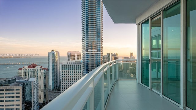 balcony at dusk featuring a water view