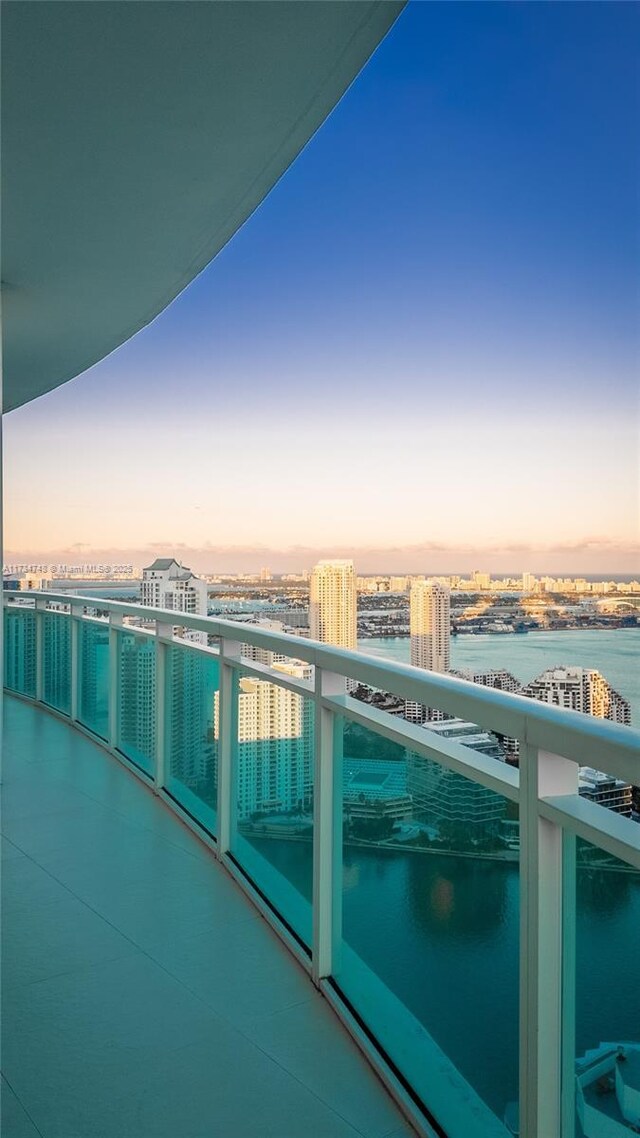 balcony at dusk featuring a water view