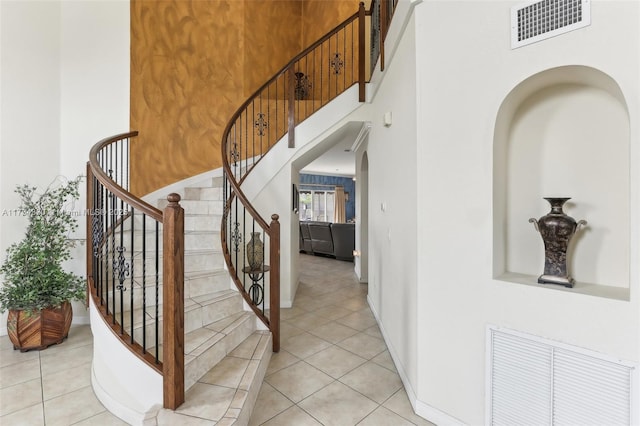 stairway with tile patterned flooring and a high ceiling