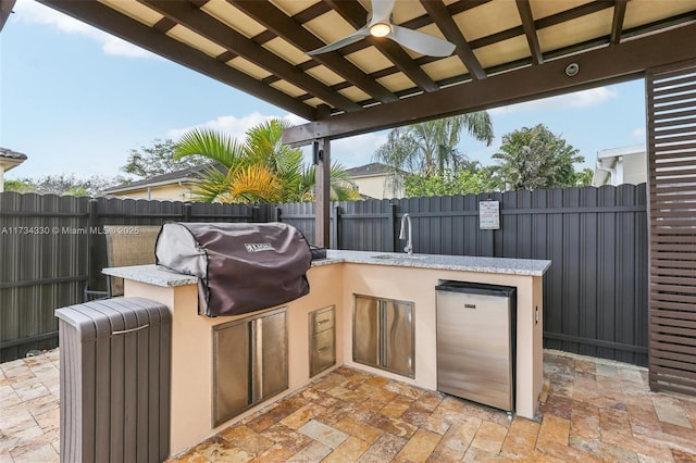 view of patio / terrace featuring ceiling fan, a grill, exterior kitchen, and sink