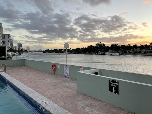 patio terrace at dusk featuring a water view