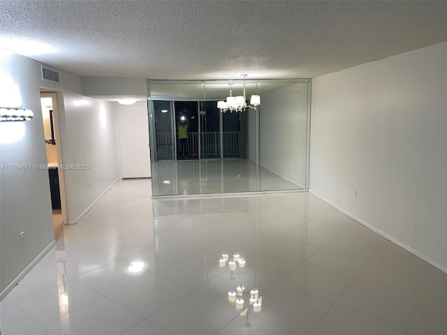 unfurnished room with tile patterned flooring, a notable chandelier, and a textured ceiling