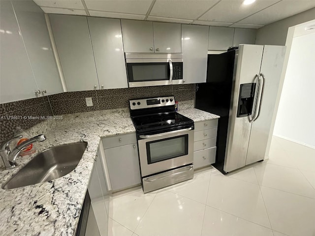 5838 Collins Ave Unit 3D, Miami Beach, FL 33140 - kitchen with appliances with stainless steel finishes, gray cabinetry, light tile patterned floors, light stone counters, and a drop ceiling