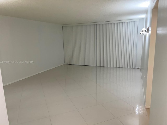 tiled empty room featuring a textured ceiling