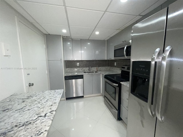 kitchen with gray cabinets, sink, decorative backsplash, stainless steel appliances, and a drop ceiling