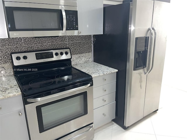 kitchen with tasteful backsplash, white cabinetry, appliances with stainless steel finishes, and light stone counters